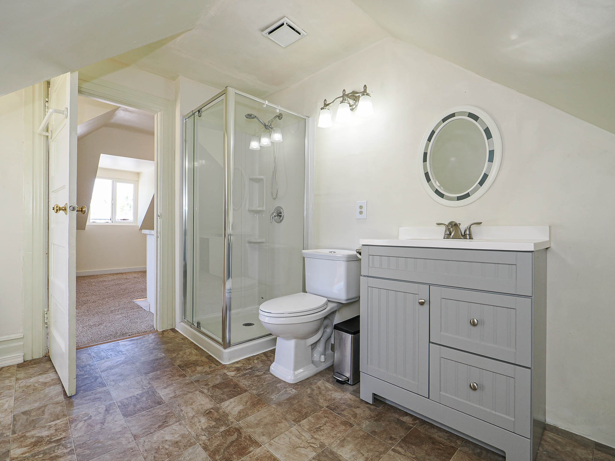 Bathroom featuring a glass-enclosed shower, a vanity with a light gray cabinet and white countertop, and patterned floor tiling