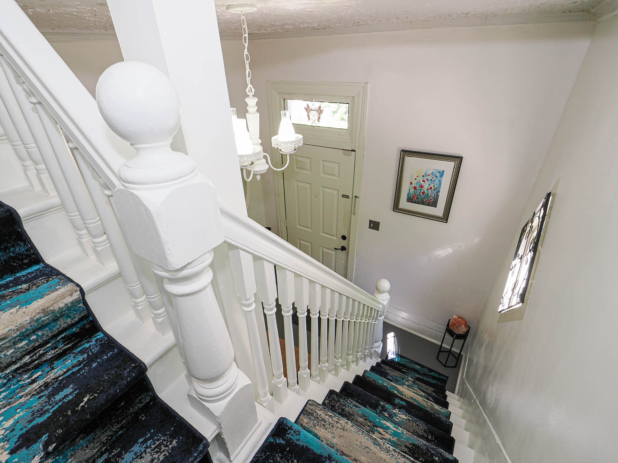 Staircase featuring white balusters and a colorful runner