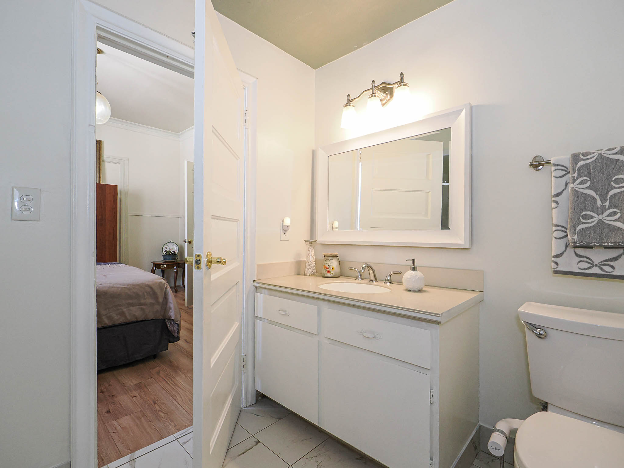 Bathroom with a white vanity featuring an integrated sink and brushed nickel faucet, set against white walls