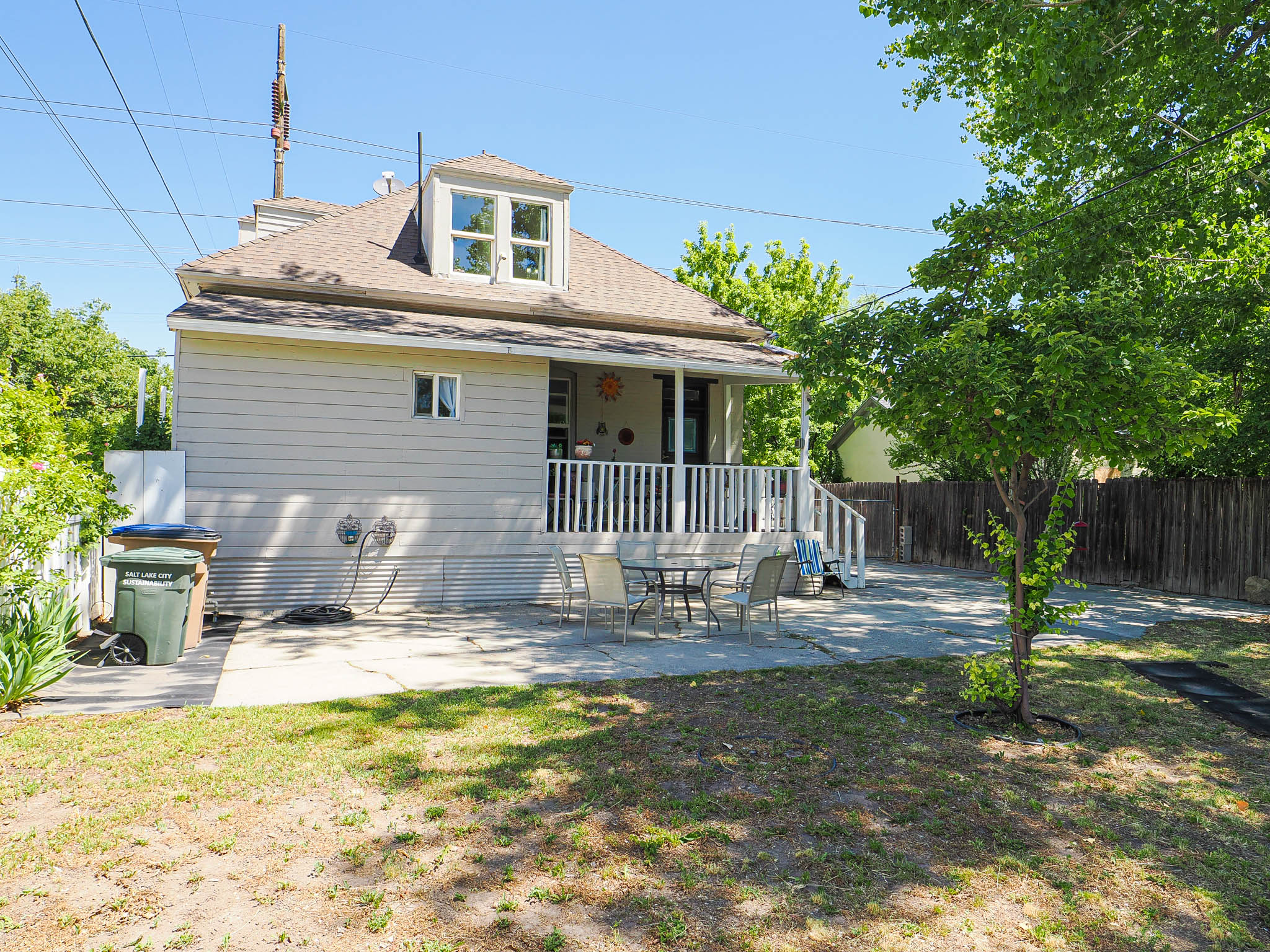 Rear exterior featuring a dormer window, covered porch with white railings, and a concrete patio