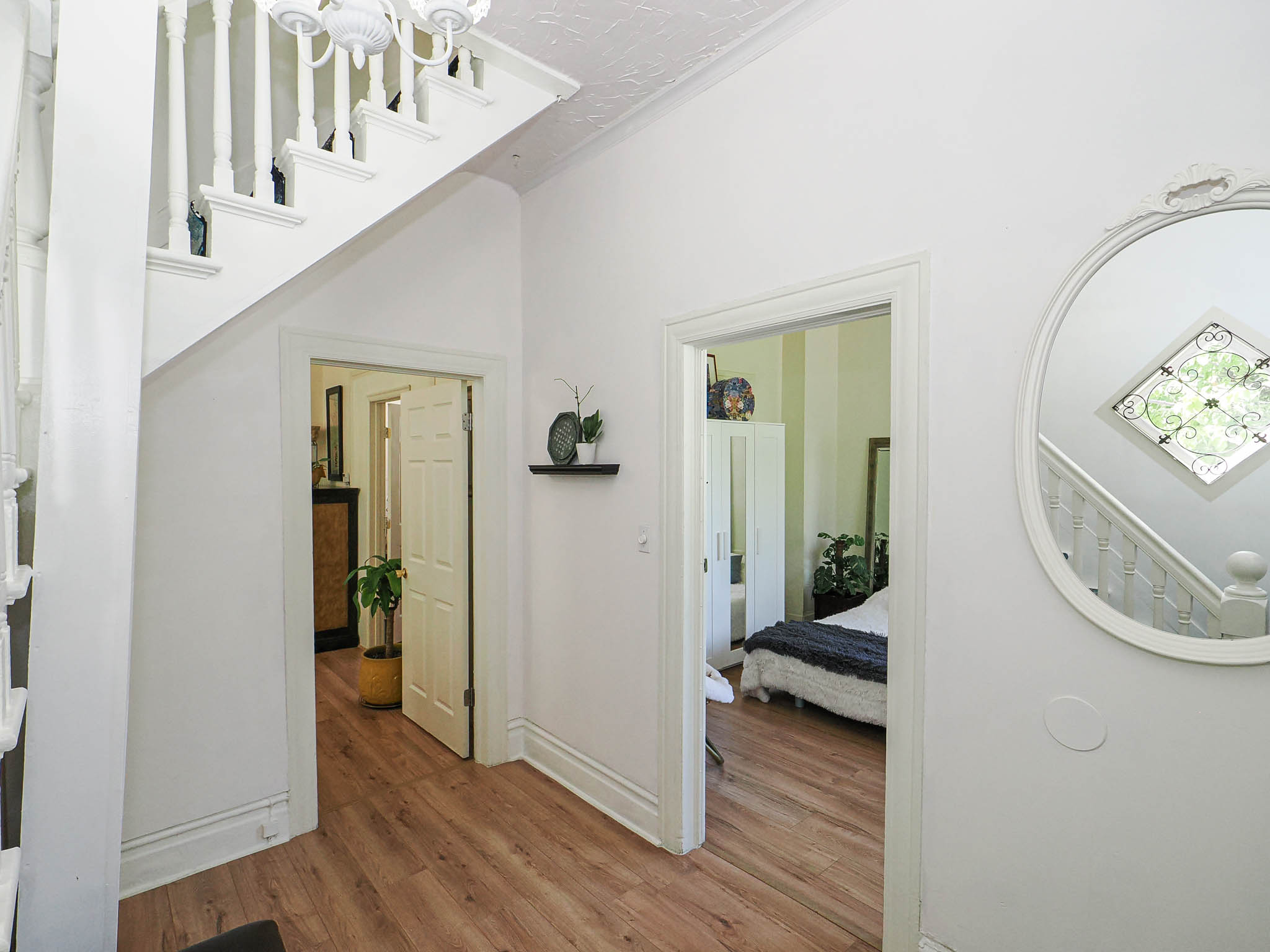 Entryway featuring wood-finish flooring, white painted staircase with traditional balusters, and a decorative ceiling light fixture