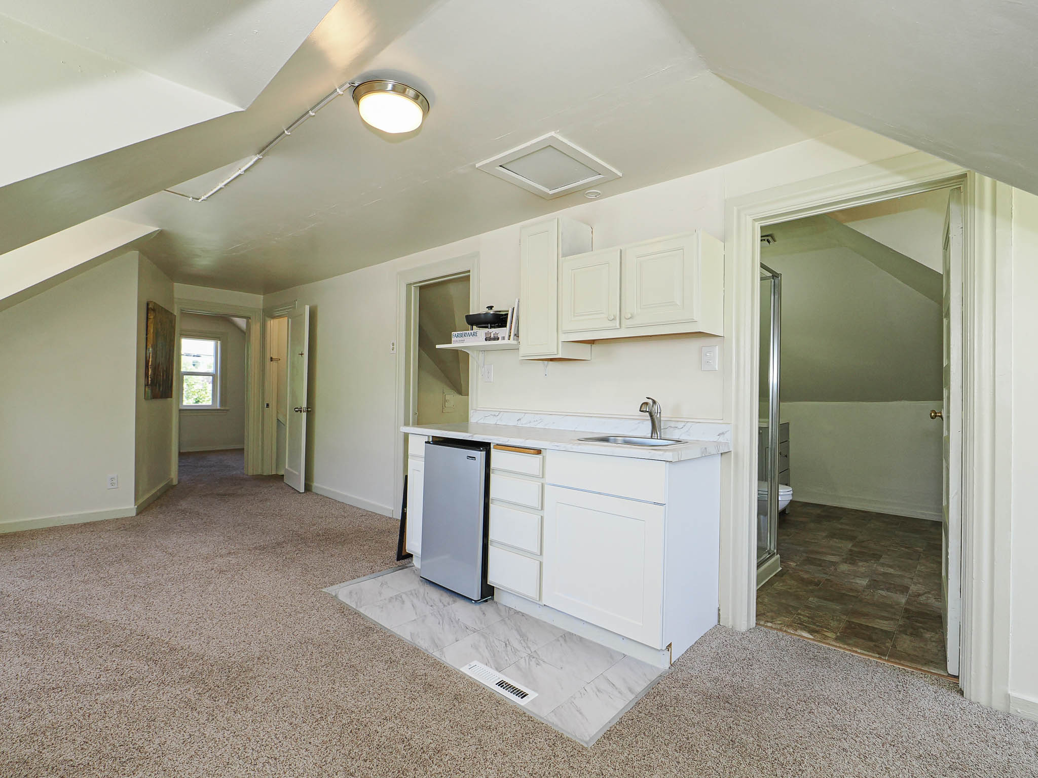 Attic area featuring a built-in wet bar with white cabinetry, a sink, and a light-toned countertop