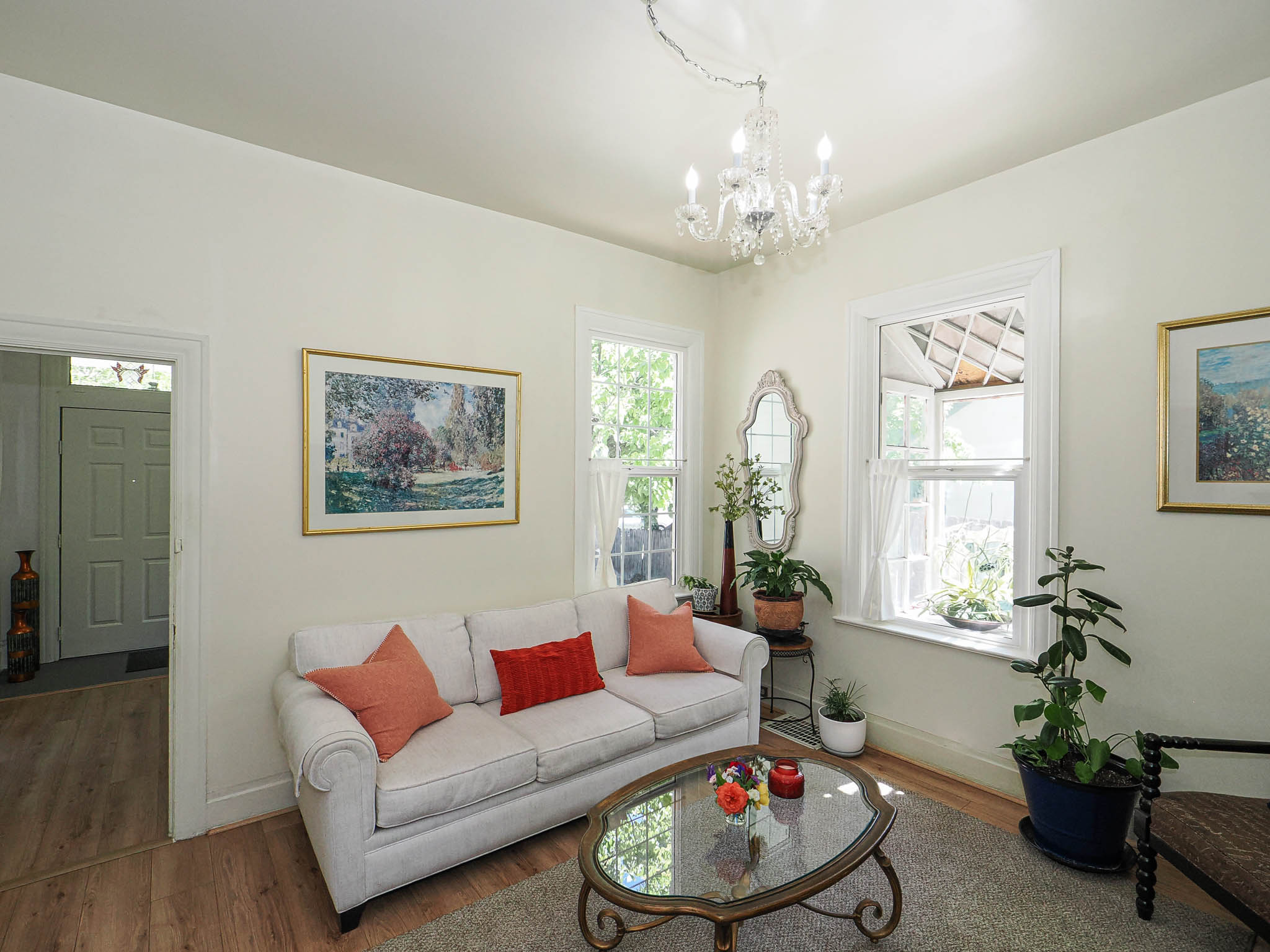 Bright interior space featuring light-toned walls, wood-finish flooring, and a crystal chandelier