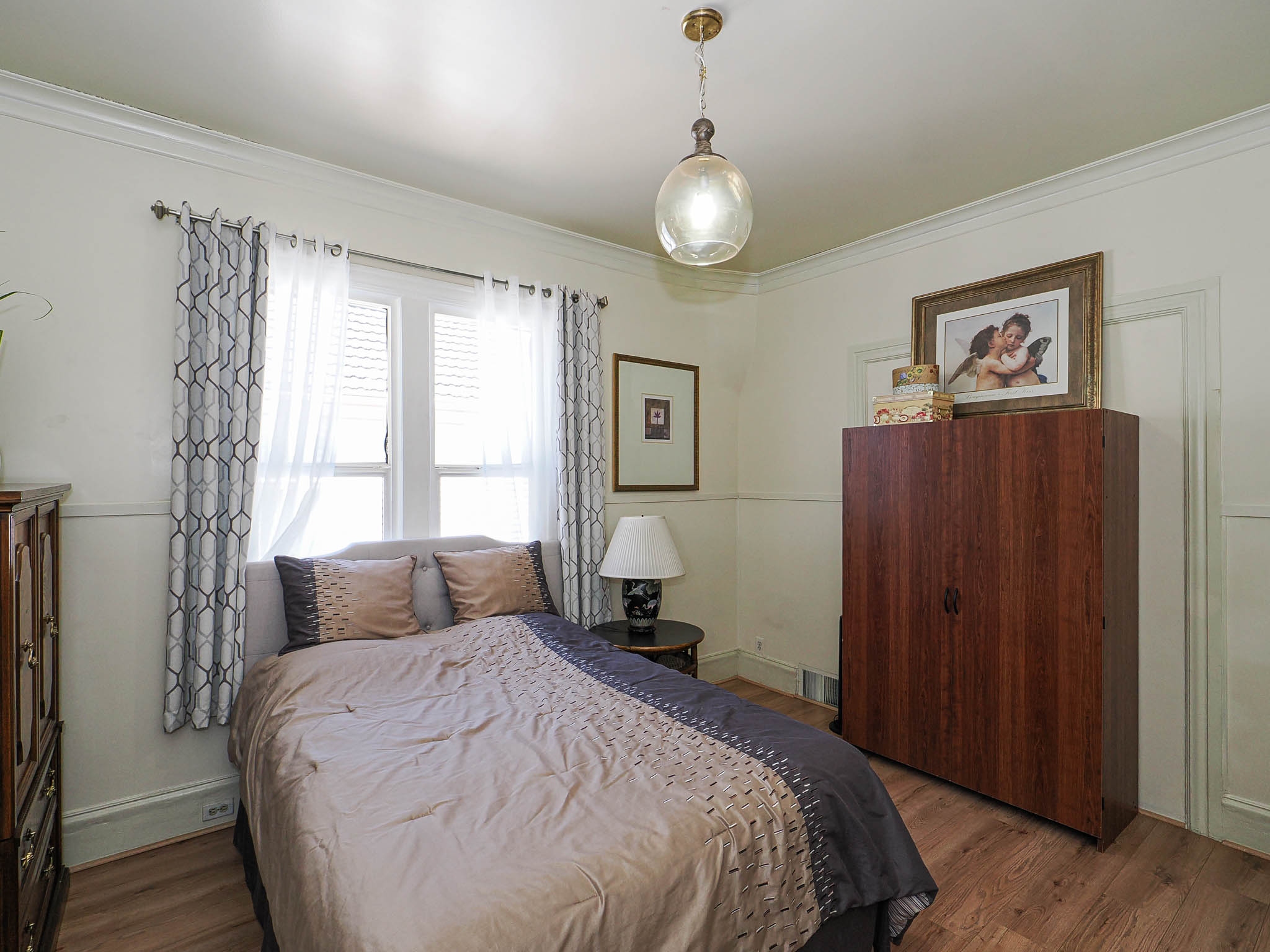 Bright room featuring a window with white shutters, wood-finish flooring, and crown molding