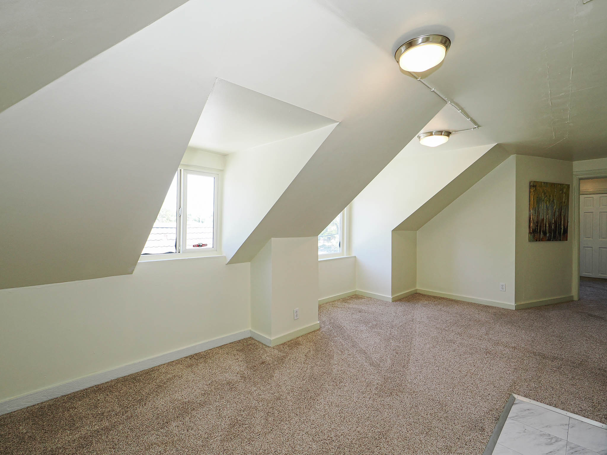 Carpeted room with sloped ceilings and two visible windows