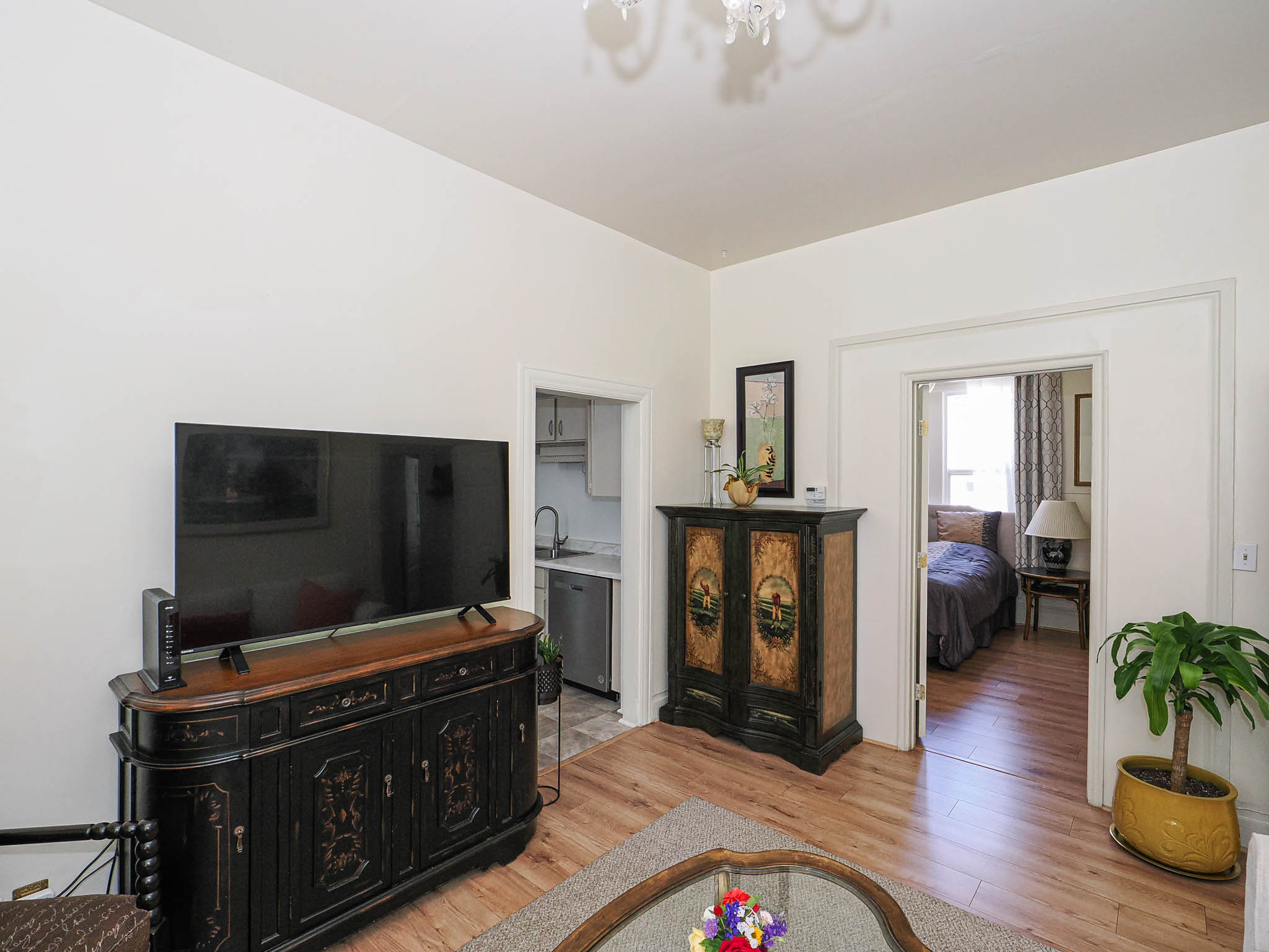 Light wood-finish flooring extends through an open doorway to a bedroom