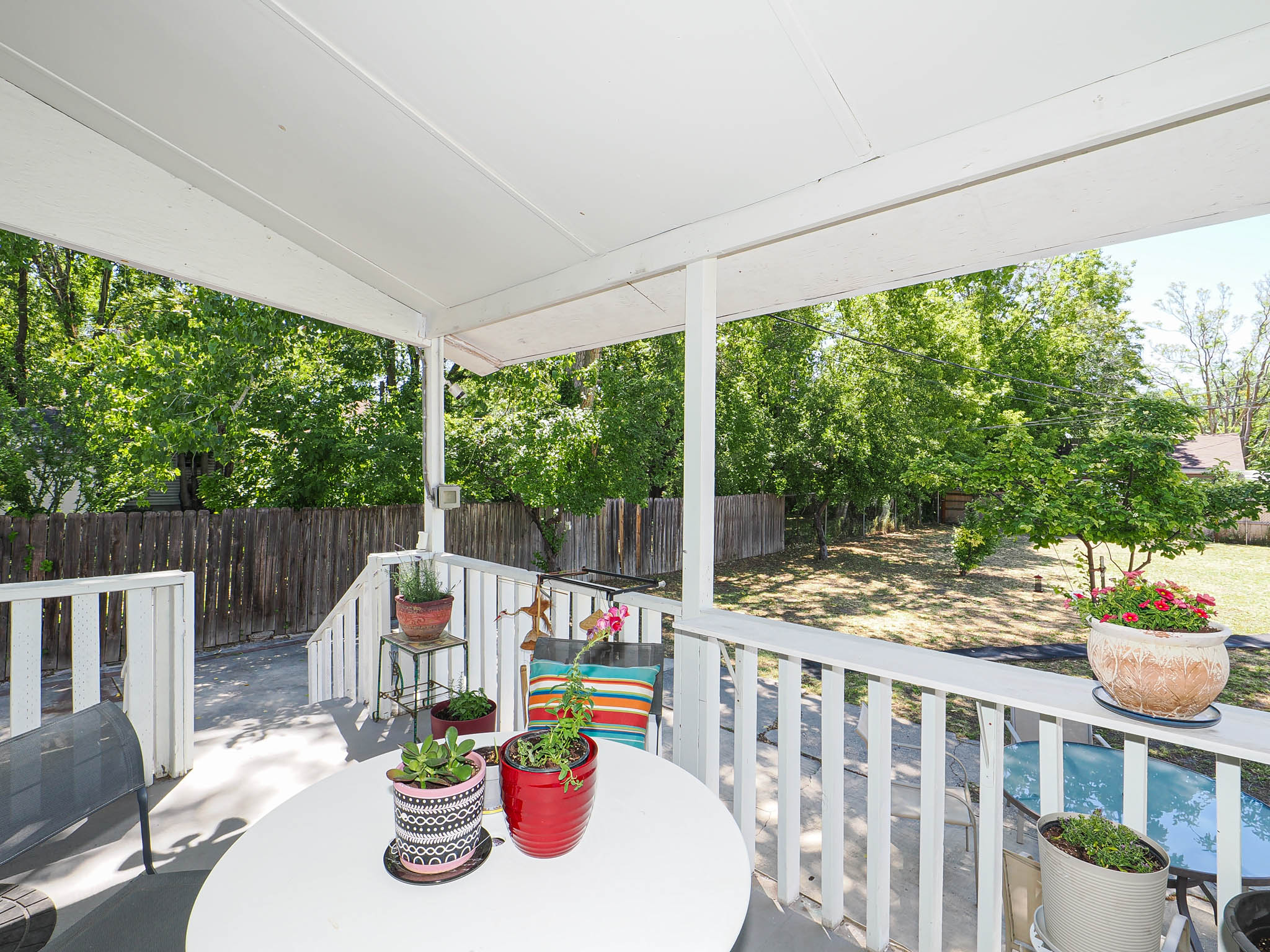 Covered patio featuring a white railing and steps to the yard