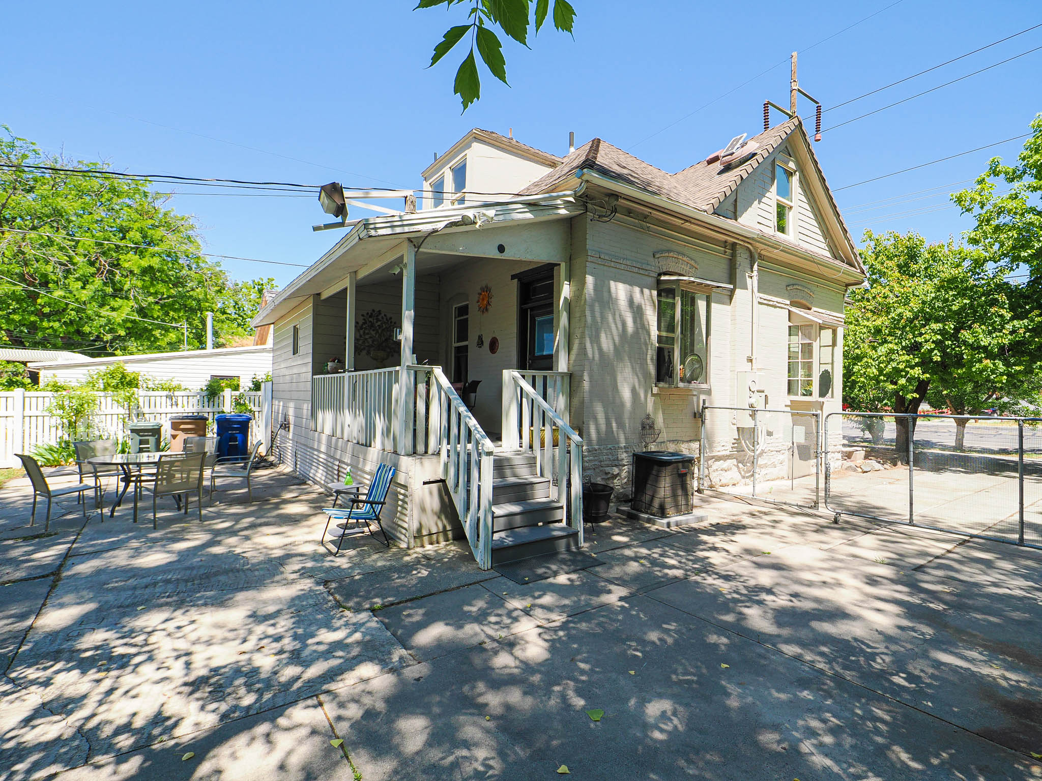 Exterior featuring a covered porch with white railings, a concrete patio, and a fenced yard