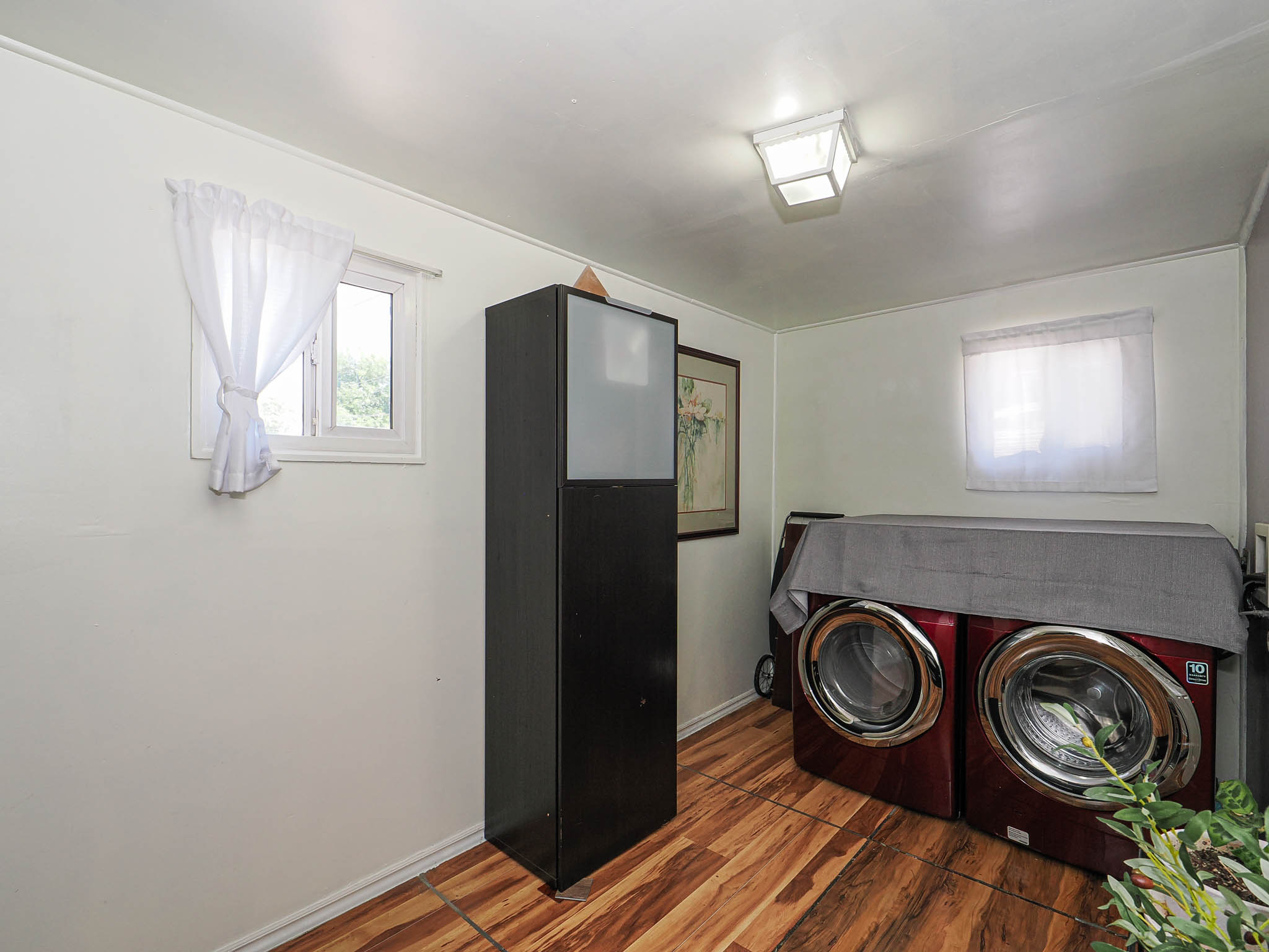 Laundry area featuring wood-finish flooring, white walls, and a ceiling-mounted light fixture