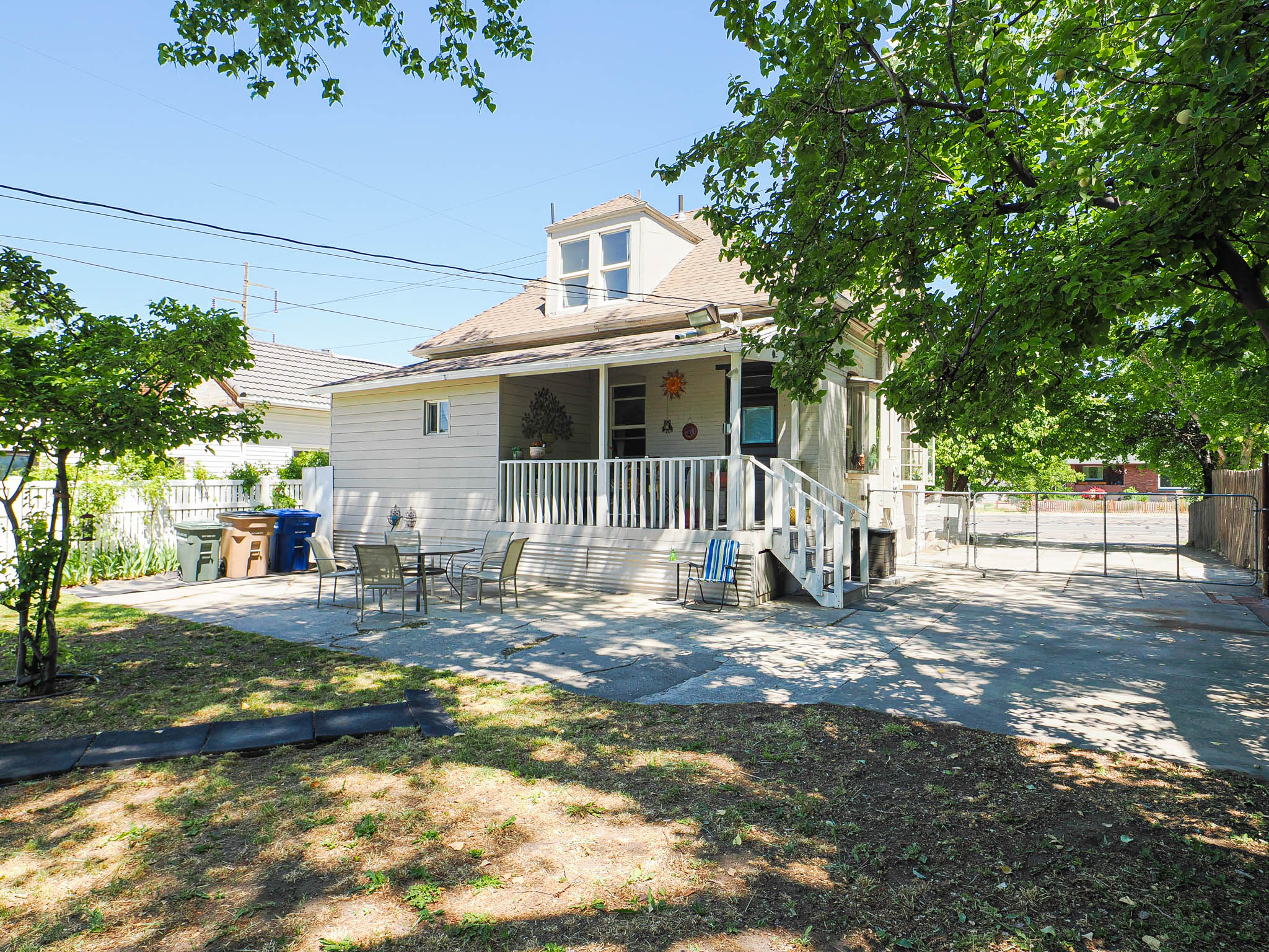 Rear exterior featuring a covered porch, white railing, and a ground-level concrete patio