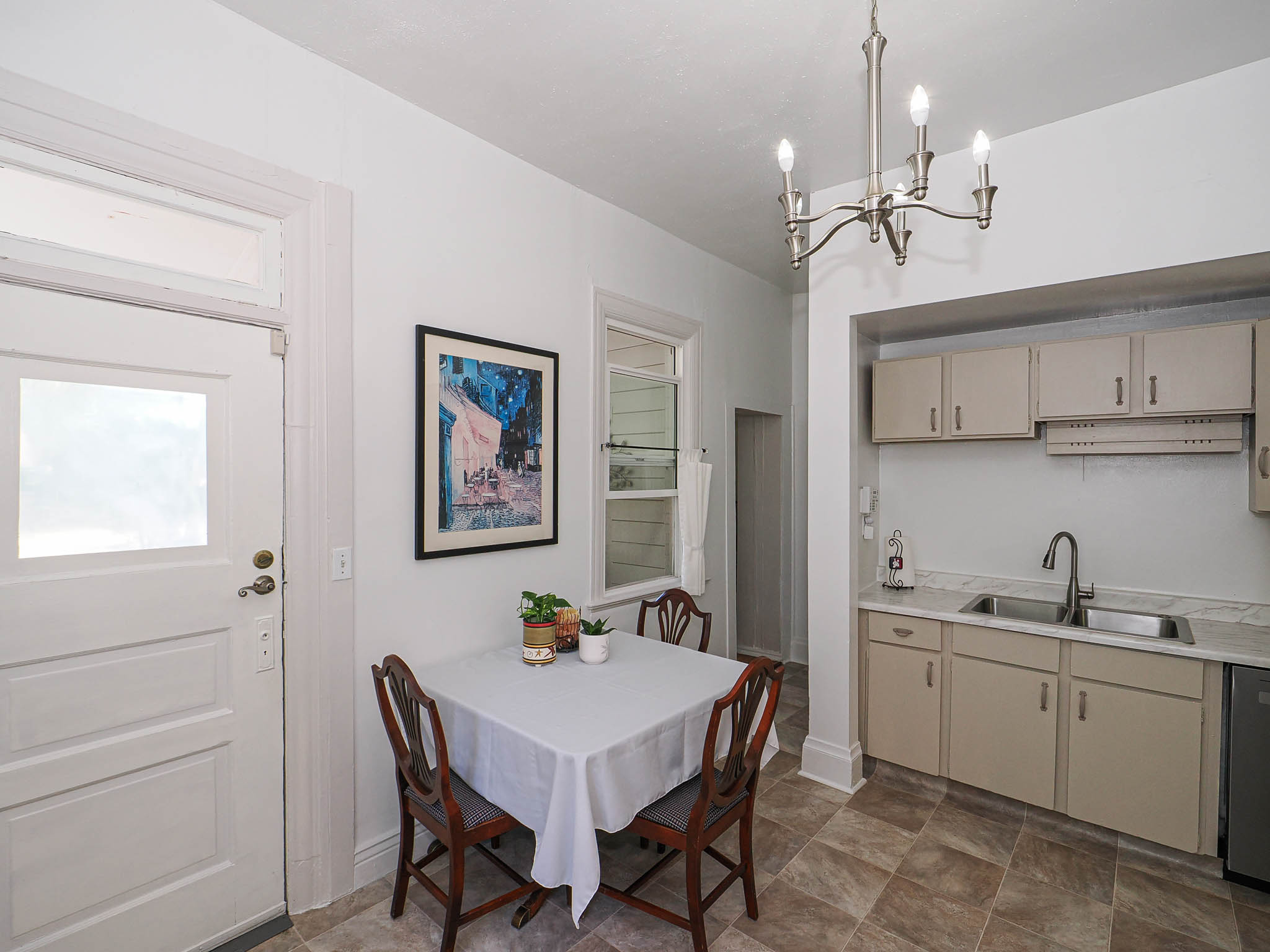 Compact kitchen area featuring a double basin stainless steel sink, beige cabinetry, and a countertop with a light-colored finish