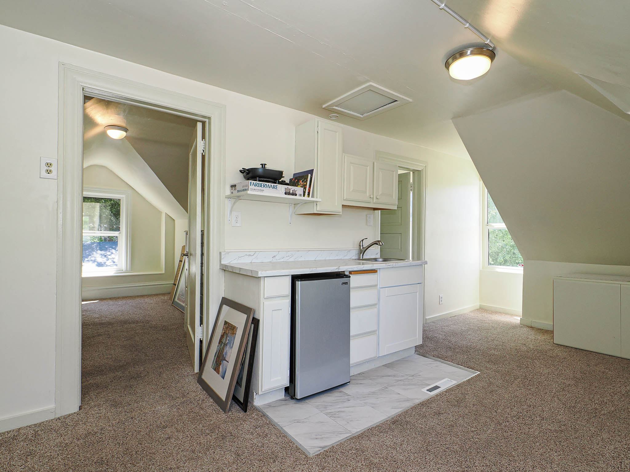 Compact wet bar featuring white cabinetry, a single basin sink with a chrome faucet, and a stone-finish countertop