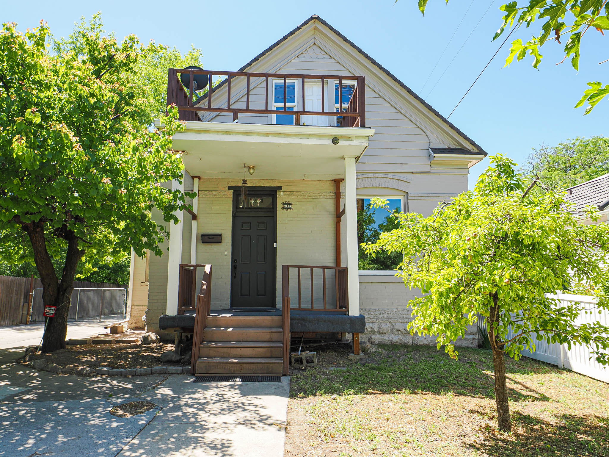 Two-story exterior featuring a second-level balcony, covered front porch, and a dark paneled entry door