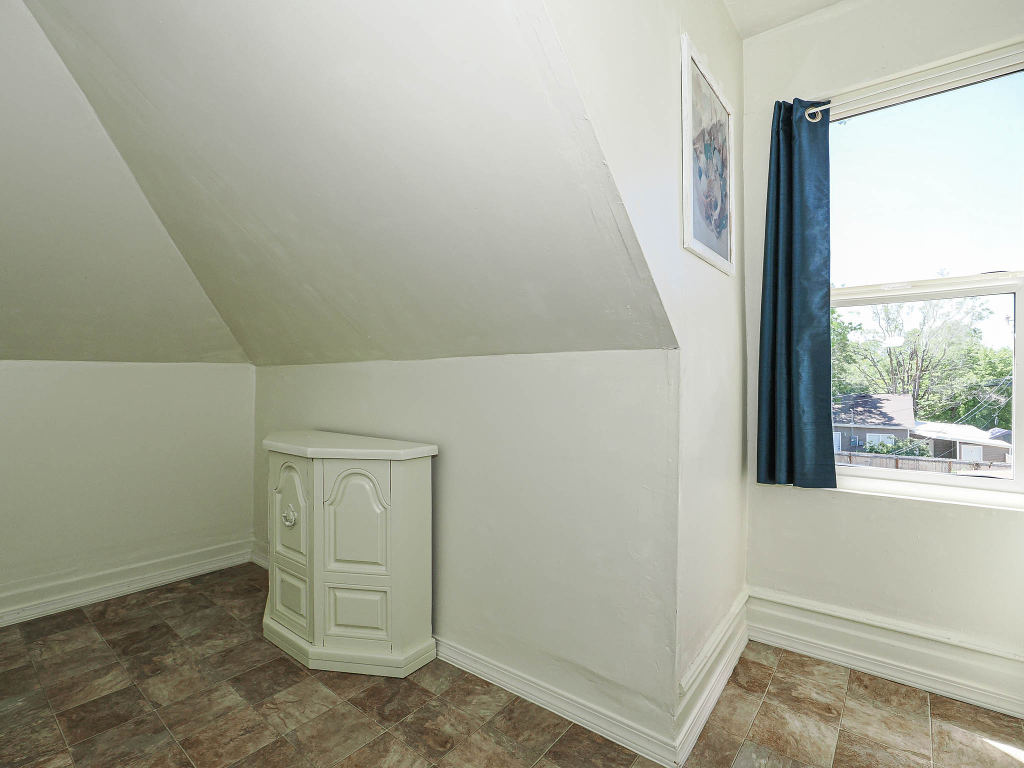 Room featuring sloped ceilings, a single window, and neutral-toned flooring