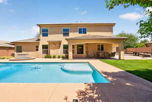 Expansive backyard with a rectangular swimming pool, integrated spa, and a covered patio