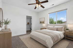 Bright bedroom with a large window, plush carpeting, and a ceiling fan