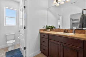 Bathroom vanity featuring a single basin, dark wood cabinetry, and a stone-finish countertop with a tiled backsplash