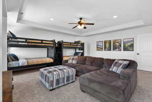 Recessed lighting illuminates this versatile room, featuring a tray ceiling and plush carpeting