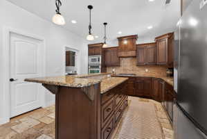 Kitchen featuring extensive wood cabinetry, stone tile flooring, granite countertops, and a built-in double oven