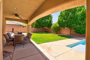 Covered patio with integrated ceiling fan, concrete flooring, and arched entryway