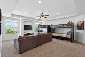 Carpeted interior space featuring white walls and a tray ceiling with recessed lighting