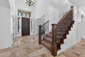 Two-story entryway featuring tile flooring, a dark wood front door, and a wrought iron and wood staircase