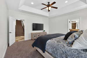 Bedroom with tray ceiling, recessed lighting, and a ceiling fan