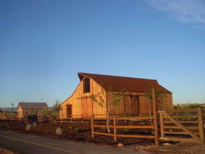 Wooden barn structure featuring a curved metal roof, upper-level window, and large sliding barn doors