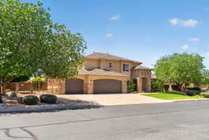 Stucco exterior featuring a stone-clad entry, arched garage doors, and a tile roof