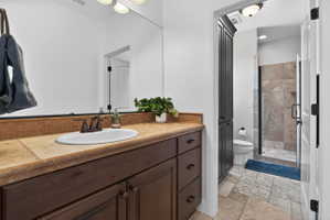 Bathroom vanity featuring a large oval sink with oil-rubbed bronze faucet, stone-finish countertop, and dark wood cabinetry with bronze hardware