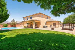 Expansive backyard featuring a lush lawn, a sparkling swimming pool, a covered patio, and a gravel area
