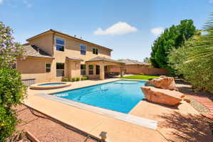 Expansive backyard featuring a rectangular swimming pool, integrated spa, and a covered patio