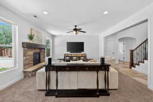 Spacious living area featuring a stone-clad fireplace with a wood mantel, recessed lighting, and a ceiling fan