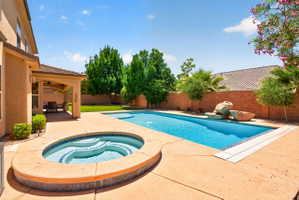 Expansive backyard featuring a rectangular swimming pool with integrated spa, a covered patio, and a manicured lawn