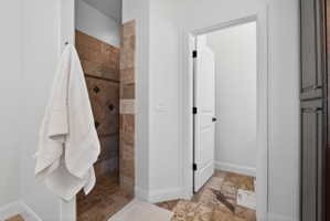 Walk-in shower with natural stone tile surround and accent band