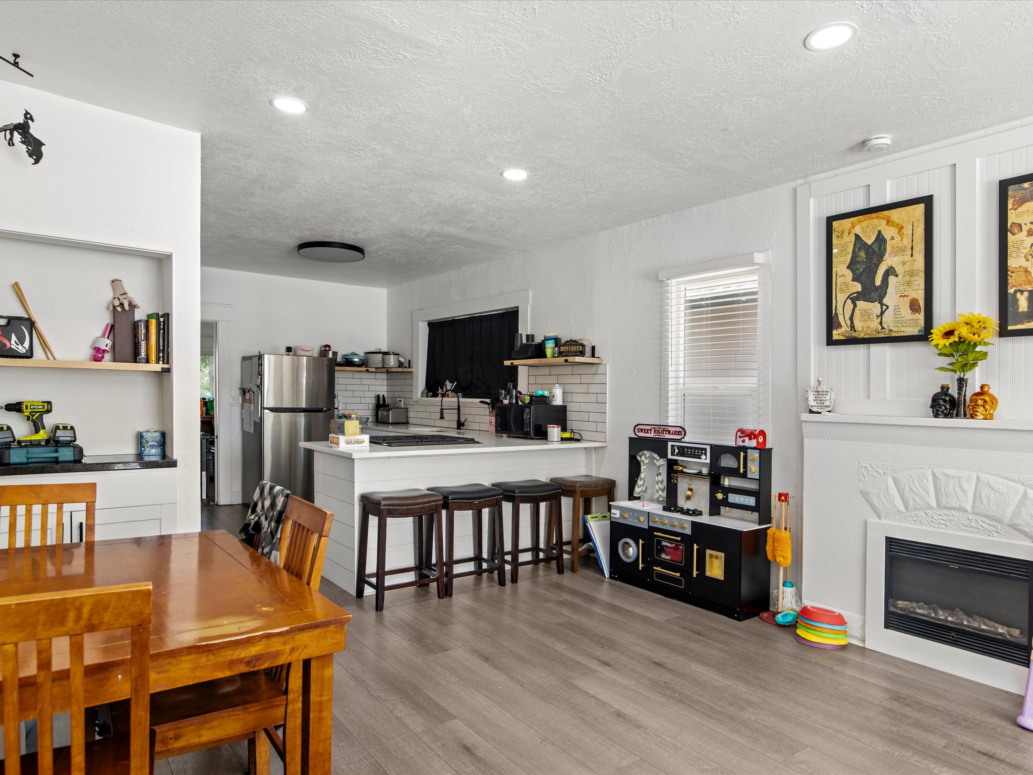 Open-concept living space featuring wood-finish flooring, recessed lighting, and a white decorative fireplace