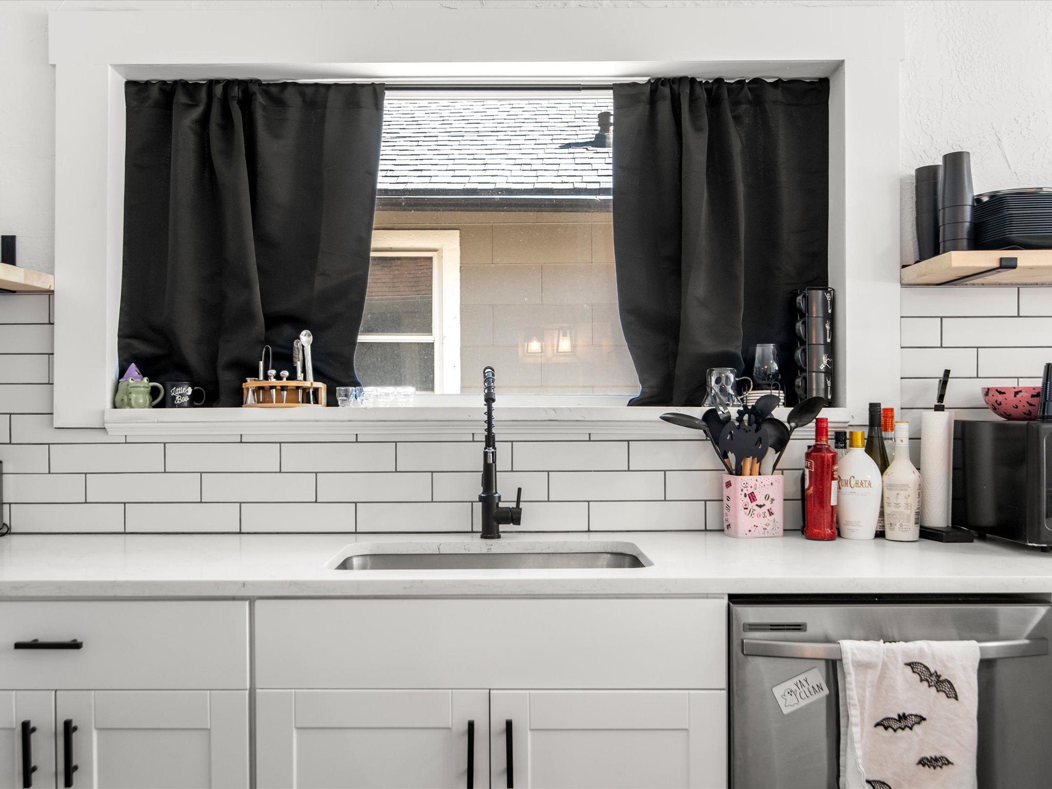 Kitchen featuring a single basin stainless steel sink, matte black faucet, and white subway tile backsplash