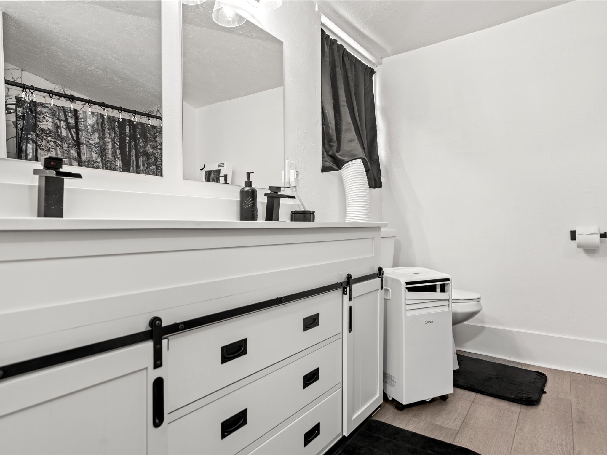 White vanity with barn door hardware, dual rectangular sinks, matte black faucets, and rectangular mirrors