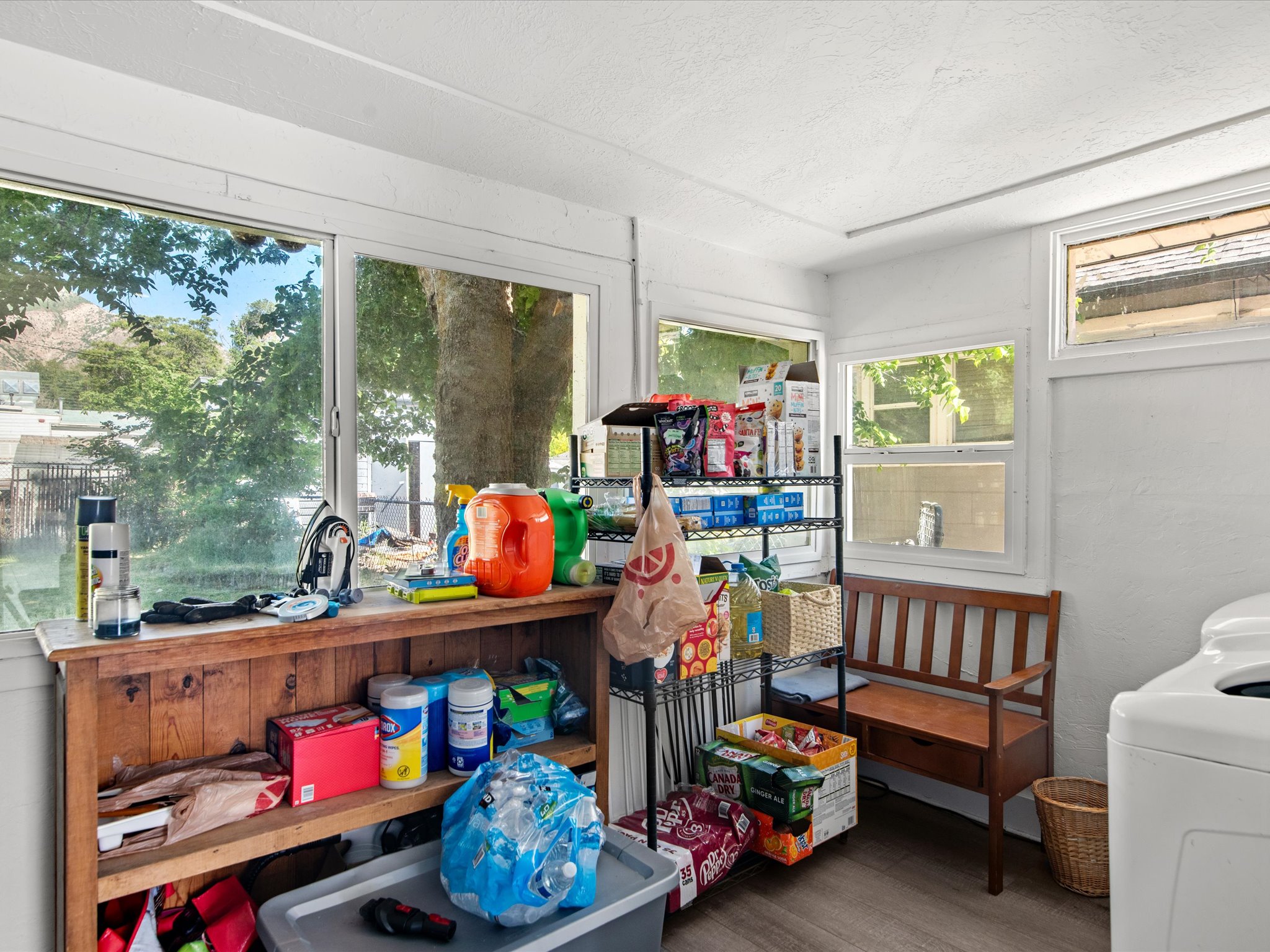 White-painted interior space featuring multiple windows, wood-finish flooring, and a built-in wood-tone shelf unit