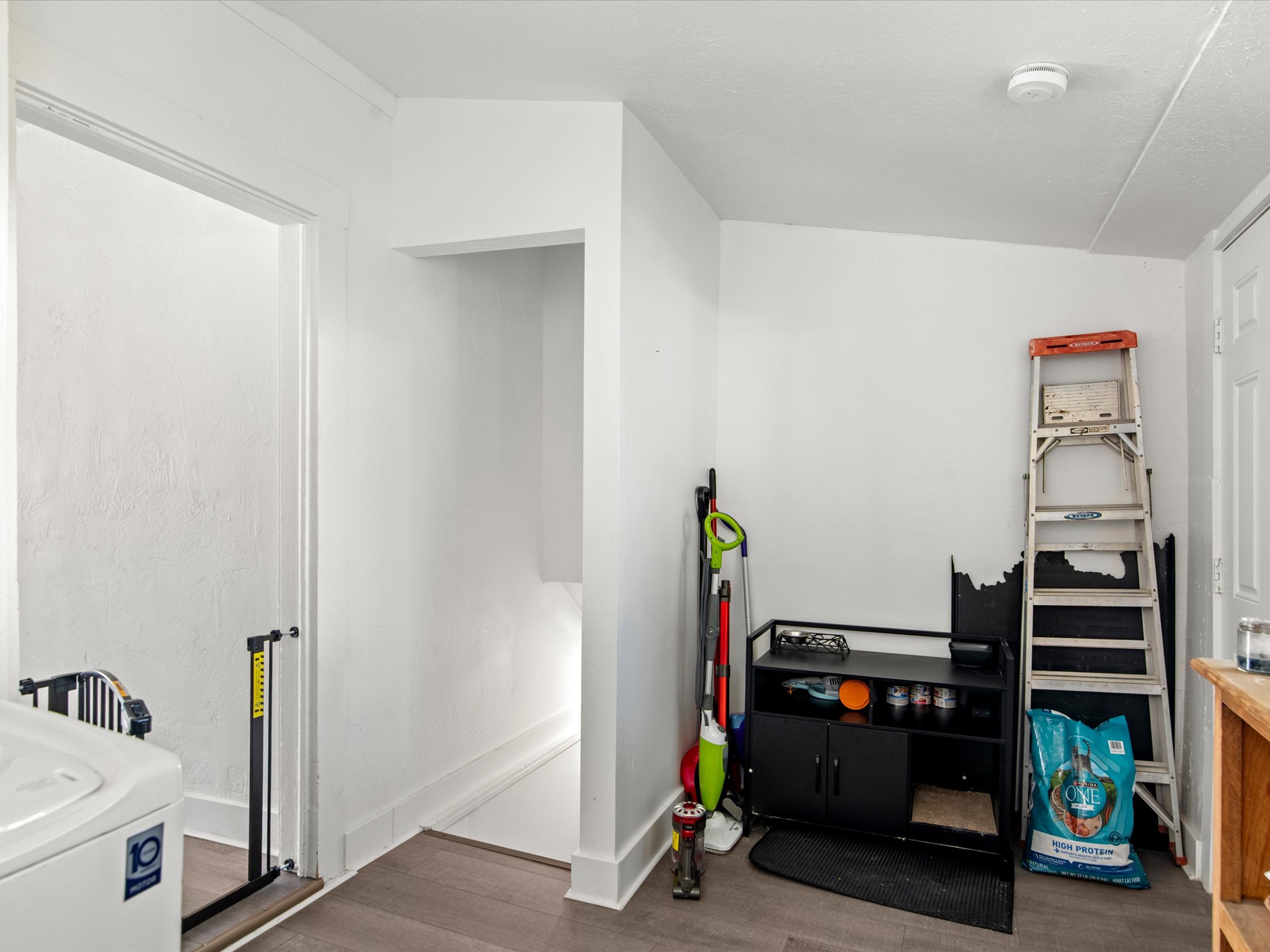 White wall finishes with wood-finish flooring, featuring a doorway and an open alcove