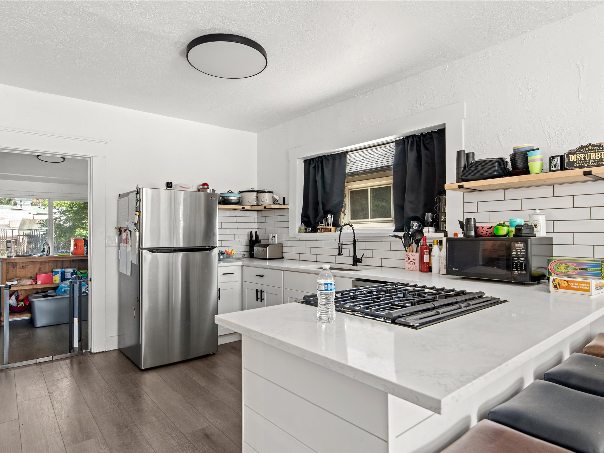 Kitchen featuring white cabinetry, a built-in gas cooktop, light-colored countertops, and white subway tile backsplash