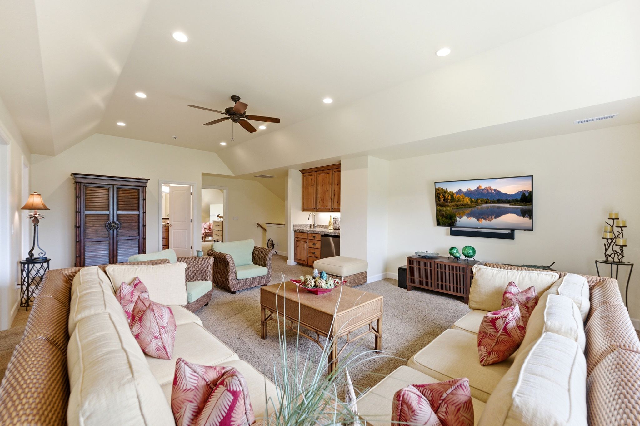 Spacious living area featuring neutral carpeting, recessed lighting, a ceiling fan, and a built-in wet bar with wood cabinetry and a countertop