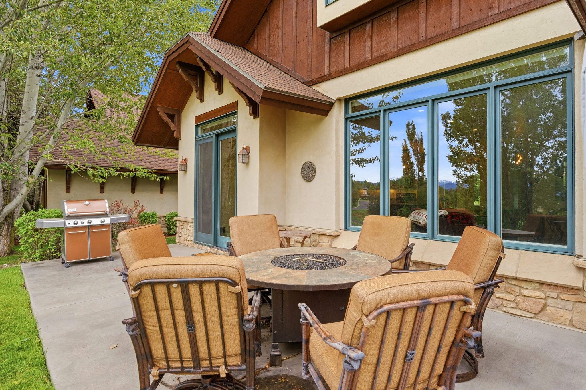 Patio area featuring a stone-clad exterior, large framed windows, and a prominent outdoor fire pit