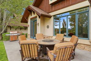 Patio area featuring a stone-clad exterior, large framed windows, and a prominent outdoor fire pit