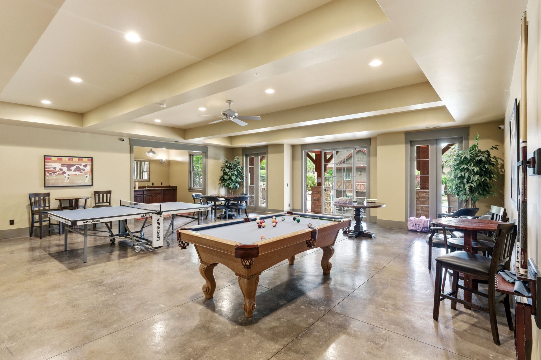 Spacious entertainment room featuring concrete flooring, recessed lighting, and a ceiling fan