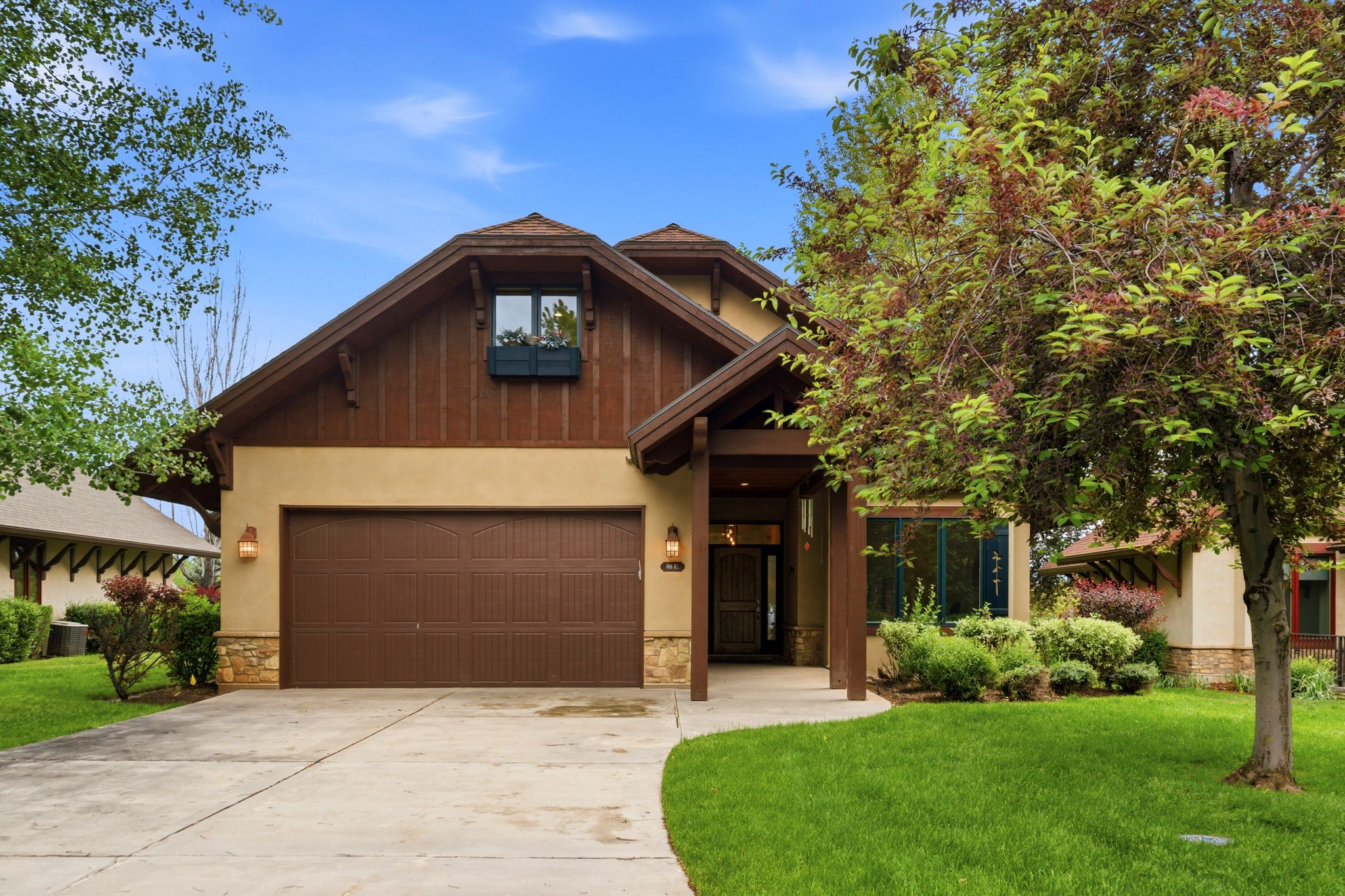 Craftsman-style exterior featuring a stucco and stone facade with wood-paneled gables