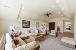 Spacious living area featuring vaulted ceilings, recessed lighting, ceiling fan, and carpet flooring