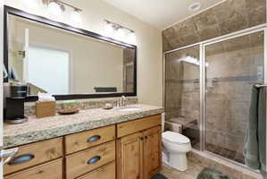 Bathroom featuring a wood-finish vanity with a light-toned countertop, an integrated sink, and a large framed mirror