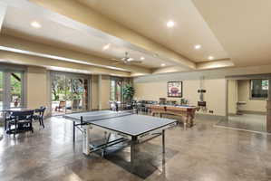 Spacious entertainment room featuring exposed concrete flooring, recessed ceiling lighting, and multiple large glass sliding doors providing abundant natural light