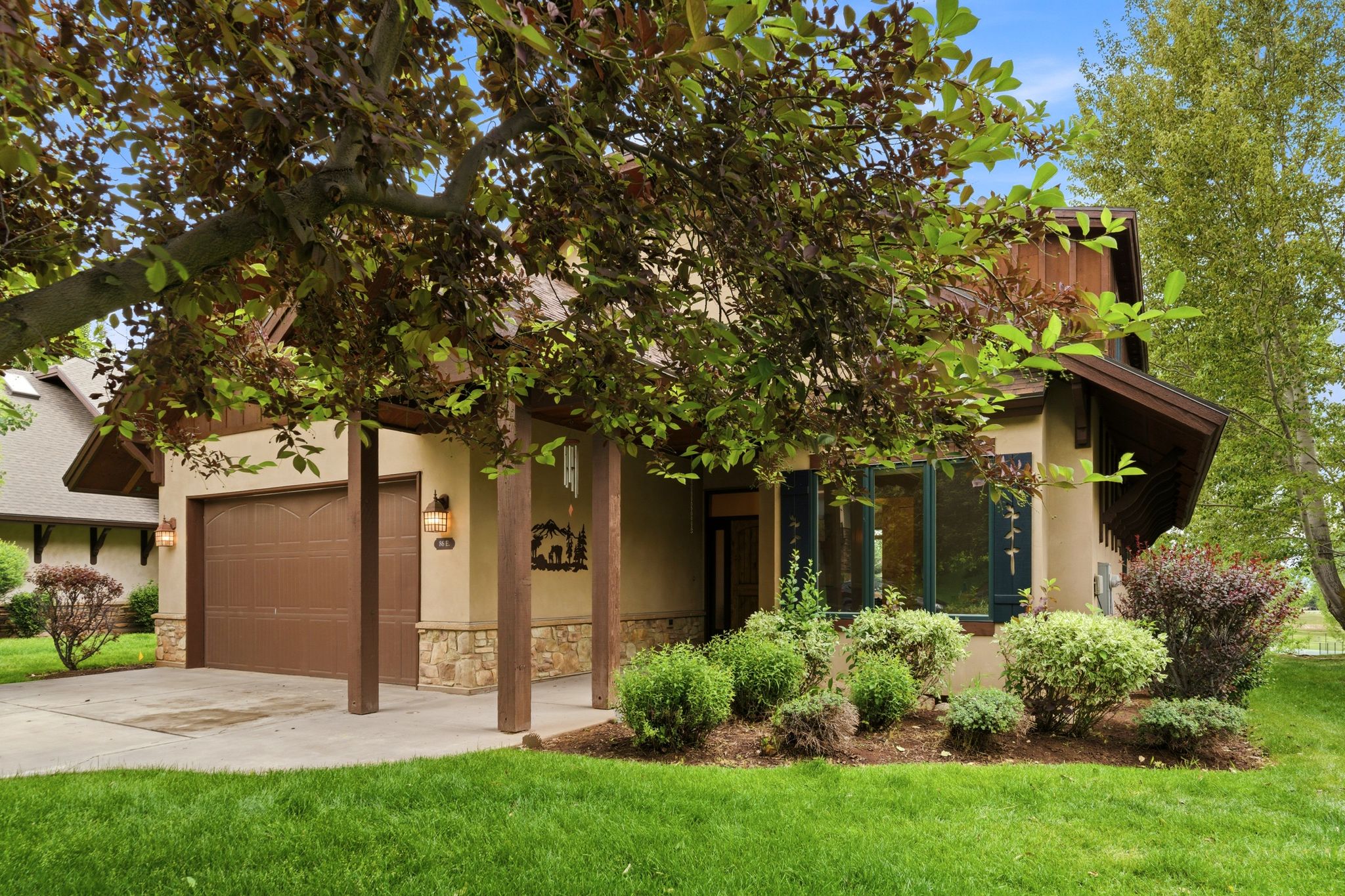 Stucco exterior featuring stone accents and a covered entry